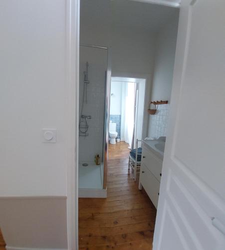 un couloir blanc avec une salle de bain, un lavabo et un miroir dans l'établissement Le Gîte Adelis, à La Celle-sous-Gouzon