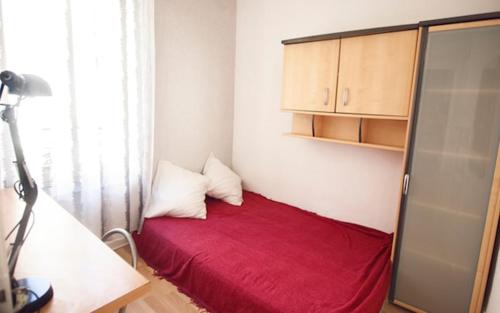 Cette petite chambre comprend un lit rouge avec deux oreillers. dans l'établissement Paisible F1 Hyper Centre 1er Étage, à Clermont-Ferrand