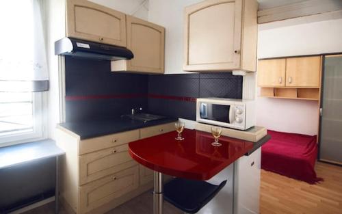 une cuisine avec une table rouge et un four micro-ondes dans l'établissement Paisible F1 Hyper Centre 1er Étage, à Clermont-Ferrand