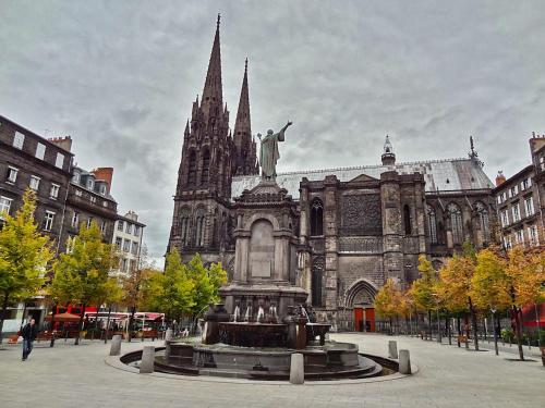 une statue devant une cathédrale avec une fontaine dans l'établissement Paisible F1 Hyper Centre 1er Étage, à Clermont-Ferrand