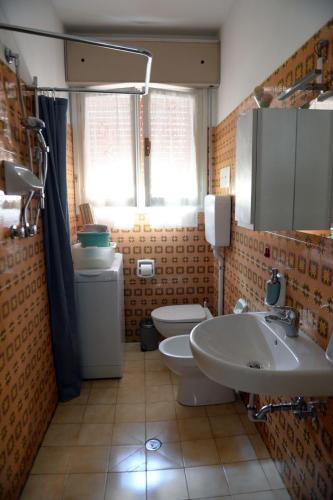 a bathroom with two sinks and a toilet and a window at Appartamento Climatizzato con Piscina Ca' Aurelia in Lido di Savio
