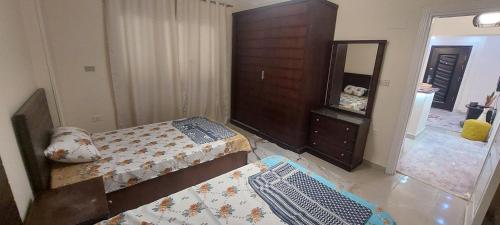 a bedroom with two beds and a dresser and a mirror at شقة فندقية بمدينة الشروق in Madīnat ash Shurūq