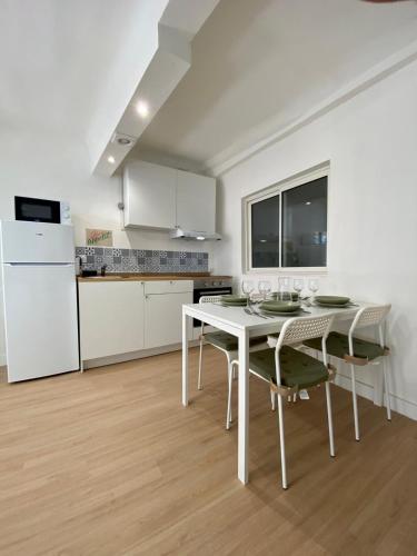 une cuisine et une salle à manger avec une table et des chaises blanches dans l'établissement Appartement pour 4 rue arc en ciel, à Draguignan
