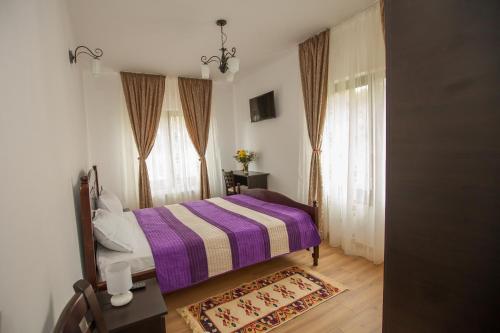 een slaapkamer met een bed met een paars gestreepte deken bij Pensiunea Aurora in Racova