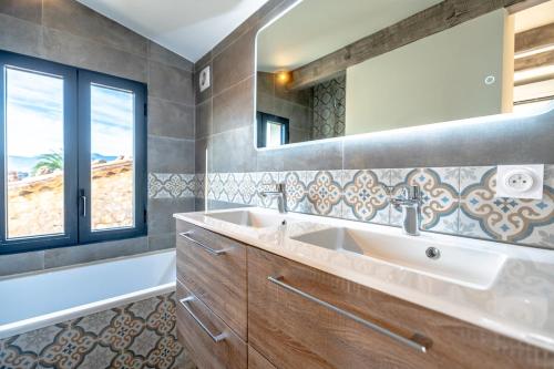 une salle de bain avec un lavabo, une baignoire et un miroir dans l'établissement Magnifique Maison de Village climatisée, terrasse, au Plan-de-la-Tour