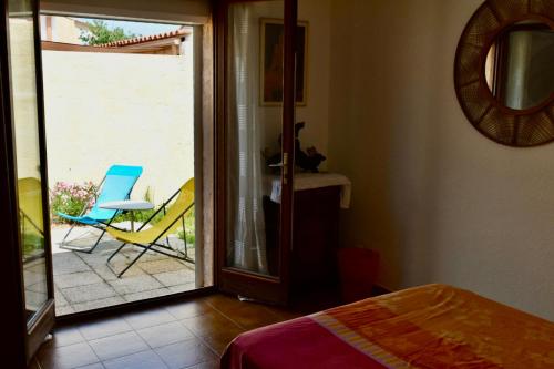 une chambre avec une porte donnant sur un patio avec une chaise dans l'établissement Chambre chez l'habitant avec Piscine, à Bessan