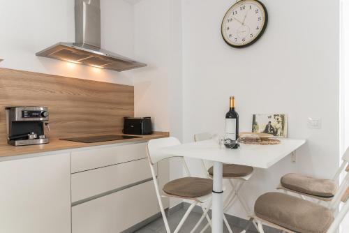 a kitchen with a table and a clock on the wall at Home2Book Bright Retreat with Roof Access in Vecindario