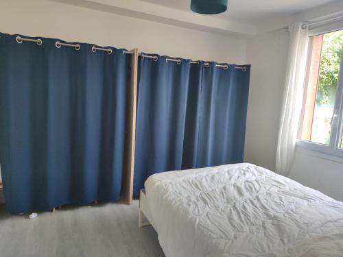 - une chambre avec des rideaux bleus, un lit et une fenêtre dans l'établissement Cozy house between Disney and Paris, à Courtry