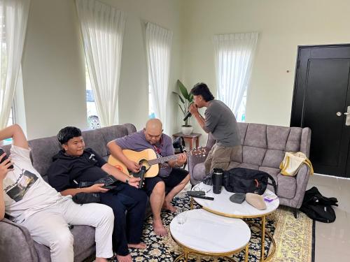 a group of people sitting in a living room playing guitar at KLIA HBO Villa Homestay in Nilai