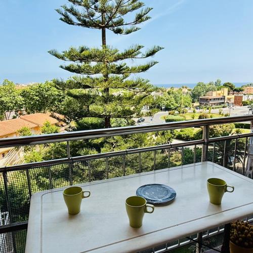 a table with two coffee cups and a pine tree on a balcony at Creu St Pol G5 Terraza y vistas junto a la playa in S'Agaro