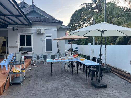 a patio with tables and umbrellas in front of a house at KLIA HBO Villa Homestay in Nilai