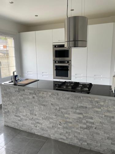 - une cuisine avec des placards blancs et un plan de travail en granit dans l'établissement Maison vert galand, à Villepinte