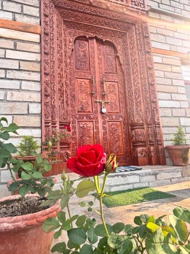 a red rose in front of a wooden door at Panchwati Farms Homestay in Almora