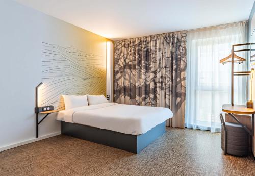 a hotel room with a bed and a window at B&B HOTEL Poitiers Aéroport in Poitiers