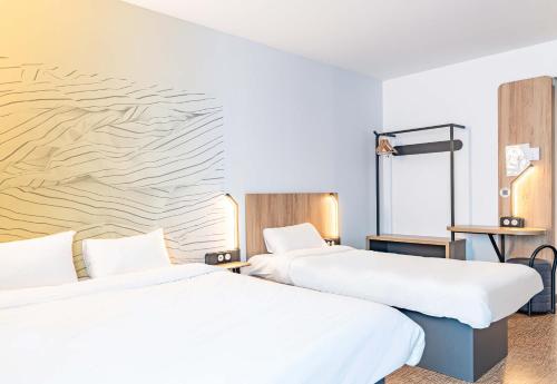 two beds sitting next to each other in a hotel room at B&B HOTEL Poitiers Aéroport in Poitiers