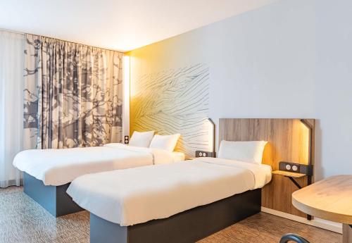 a hotel room with two beds and a table at B&B HOTEL Poitiers Aéroport in Poitiers