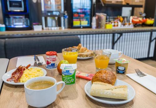 a table topped with plates of breakfast food and coffee at B&B HOTEL Poitiers Aéroport in Poitiers