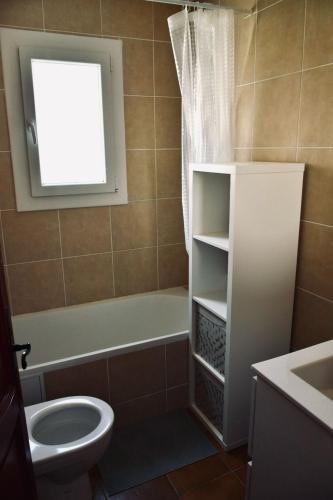 une salle de bain avec baignoire et toilettes et une fenêtre dans l'établissement Chambre chez l'habitant avec Piscine, à Bessan