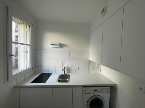 une cuisine blanche avec un évier et une machine à laver dans l'établissement Studio face Jardin des Plantes, à Paris