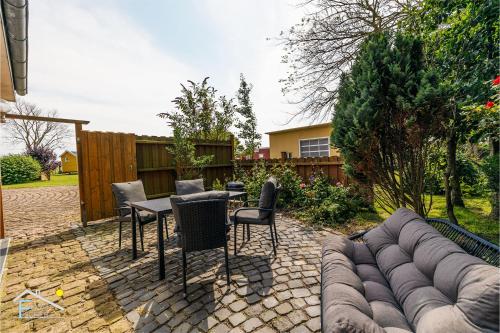 a patio with a couch and chairs and a table at De Strandloper in Westerdeichstrich