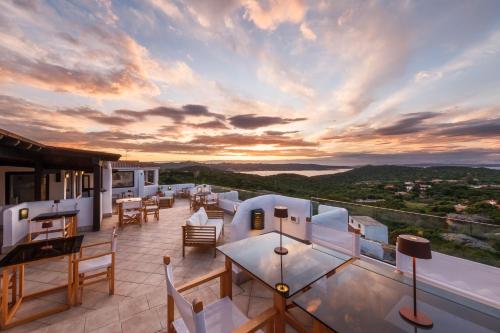 a balcony with tables and chairs and a sunset at Hotel Pedra Santa in Baja Sardinia