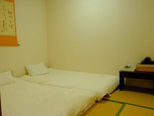 a room with two beds and a desk with a telephone at 一间民宿 in Wada