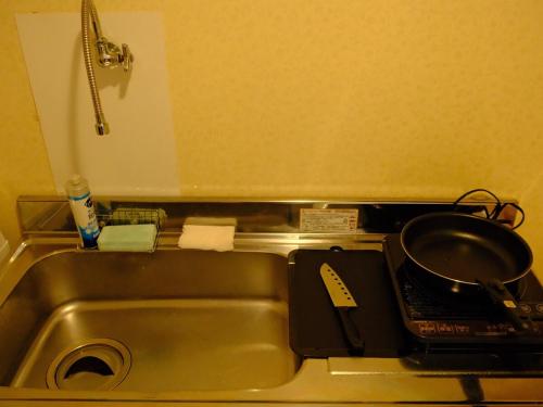 a kitchen sink with a frying pan on a stove at 一间民宿 in Wada