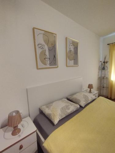 a bedroom with two beds and two pictures on the wall at Apartmani Lučica in Jezera