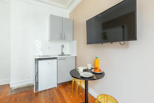 Il comprend une cuisine avec une table et une télévision murale. dans l'établissement Joli 2 pièces dans un beau quartier de Paris-II, à Paris