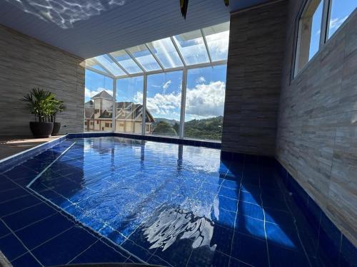 a swimming pool in a house with a large window at Kaliman Pousada Campos do Jordão in Campos do Jordão
