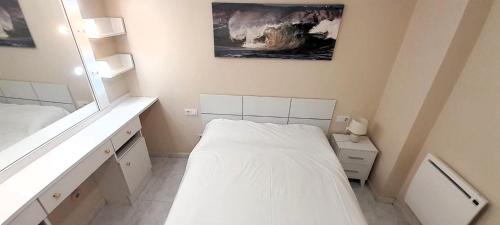 a small white room with a bed and a mirror at EnViveiro Casco Histórico in Viveiro