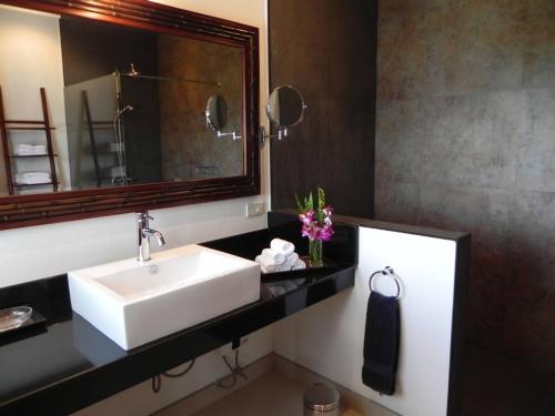 Un baño con un lavabo blanco y un espejo. en Secluded Villa with Private Pool and Breathtaking Sea Views, en Ban Thong Phlu