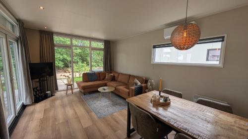 a living room with a couch and a table at Boslodge Het Groene Hert met Hottub in Haarle