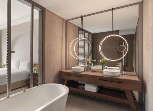 a bathroom with a tub and two sinks and a mirror at Rixos The Palm Hotel & Suites - Ultra All Inclusive in Dubai