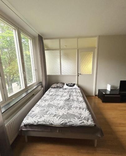 a bed in a room with two windows at Lovely apartment in the center of Ryd in Linköping