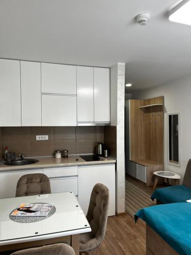 a kitchen with white cabinets and a table and chairs at Studio Bogdanovic in Vrnjačka Banja