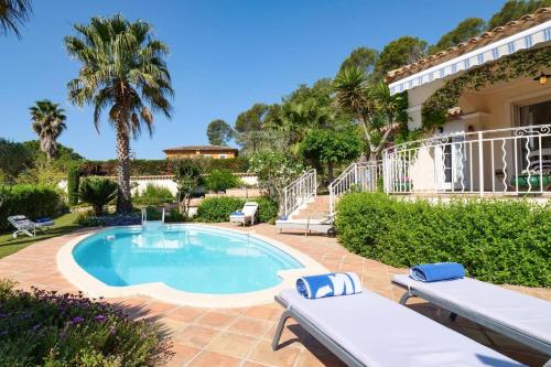 une piscine avec deux bancs et une maison dans l'établissement Villa des Vignes by Villa Plus, à La Motte