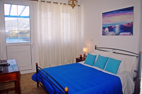 Un dormitorio con una cama azul y una ventana en Rania Studios, en Poros