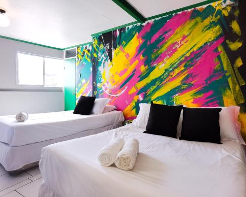two beds in a room with a painting on the wall at Hotel Velero Express in Iquique