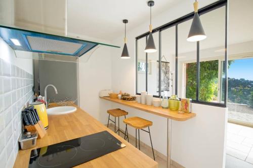 - une cuisine avec un comptoir et un évier ainsi que quelques fenêtres dans l'établissement Villa Azur by Villa Plus, à Sainte-Maxime