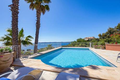 une piscine avec des palmiers et l'océan dans l'établissement Villa Sainte Maxime by Villa Plus, à Sainte-Maxime