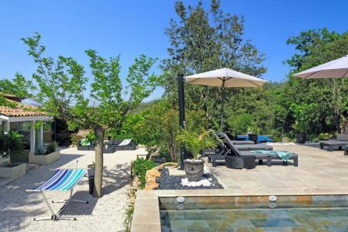 a patio with a pool and an umbrella and chairs at Villa Harmonie by Villa Plus in Flassans-sur-Issole