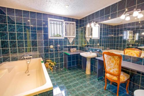 La salle de bains est pourvue de carrelage bleu, d'une baignoire et d'un lavabo. dans l'établissement Villa Sur la Colline by Villa Plus, à Les Adrets-de-l'Estérel