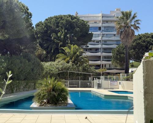 une piscine avec des palmiers et un bâtiment dans l'établissement Sol-y-Days Fleurie 1 Appartement Grande Terrasse et Parking, à La Grande Motte