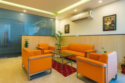 a waiting room with orange chairs and a glass table at Hotel Kian by JMD Group in New Delhi