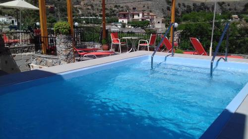 a swimming pool with blue water and red chairs at Irida in Georgioupolis