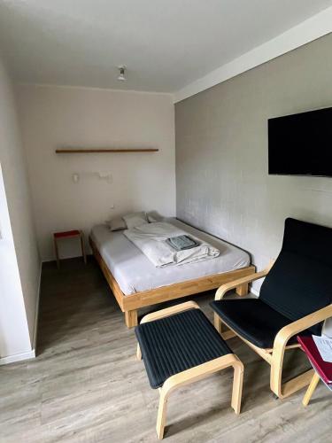 a small room with a bed and two chairs at Hempen Fied Gästehaus - Apartment 2 in Bad Zwischenahn