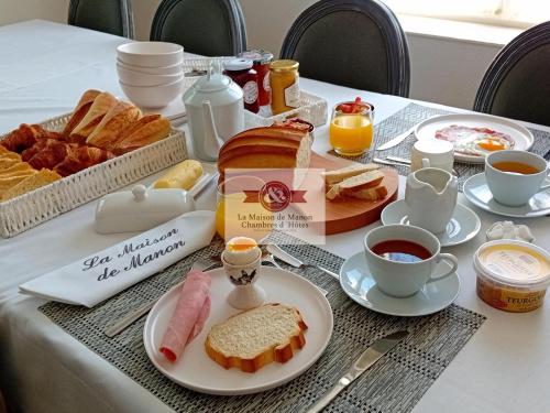 La Maison de Manon Calvados Chambres D'hôtes في Bonnebosq: طاولة إفطار مع الخبز والقهوة والخبز المحمص