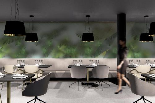 a person walking through a restaurant with tables and chairs at DAS RONACHER Thermal Spa Hotel in Bad Kleinkirchheim