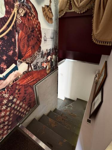 a stairway with a painting of a woman with an umbrella at Valletta Nobile by VALLETTA SUITES - a 400-year-old designer apartment in Valletta in Valletta